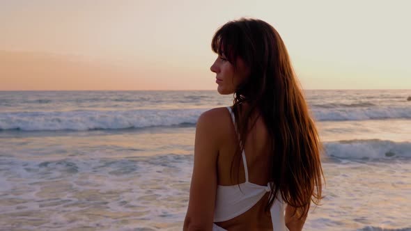 Beautiful woman in a white dress at the beach at sunset