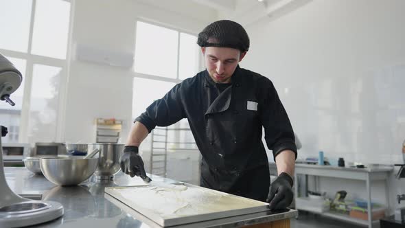 Concentrated Handsome Man Spreading Raw Dough on Metal Tray