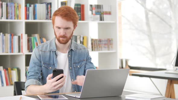 Casual Redhead Man Using Phone and Laptop