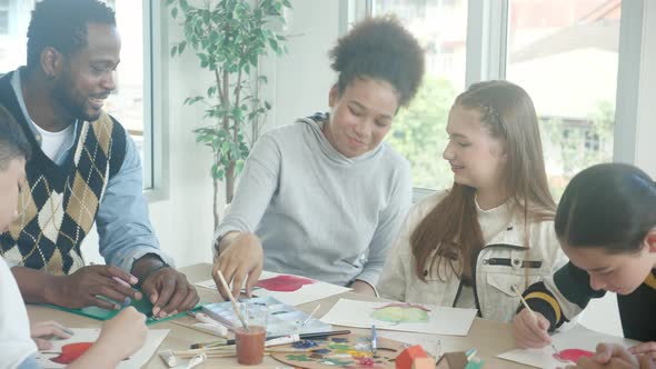 Group student girl showing drawing watercolor with teacher and friends and explaining together.