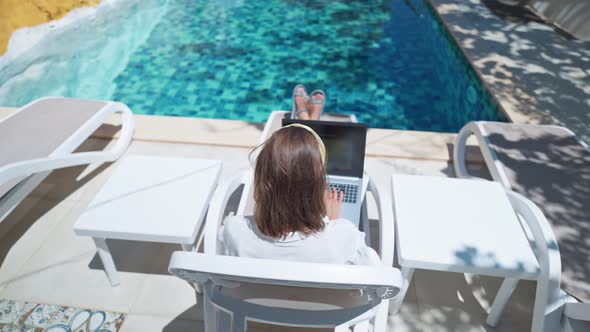 Faceless Female Using Laptop Computer Online Internet While Lying on Sun Loungers By Swimming Pool