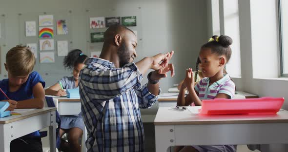 Video of happy african american teacher learning african american girl how to count in classroom