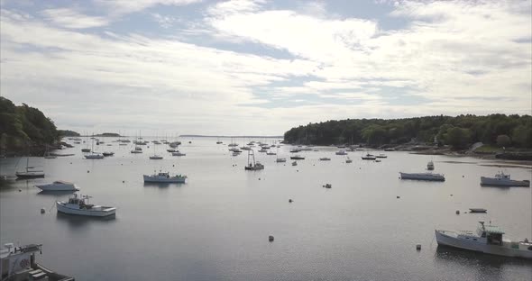 Flying out to sea over Rockport Harbor, Maine with boats below.