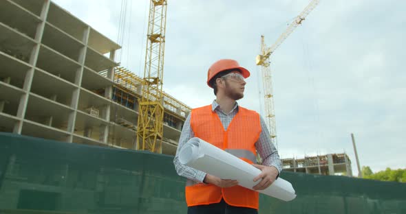 Portrait of an Architect or Builder in Hard Hat Standing in Front of Building Under Construction