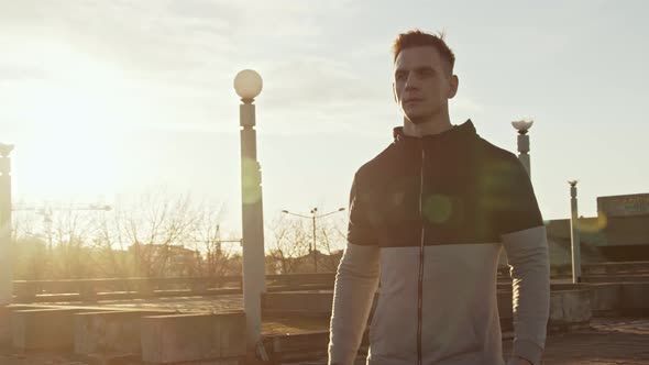 Young and fit man having evening workout outdoor. Urban sunset background.