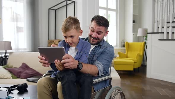 Happy Family of Son and His Father in Wheelchair which Celebrating Victory in Video Game