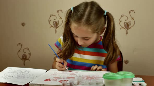 The Young Artist Enthusiastically Paints a Picture with Paints