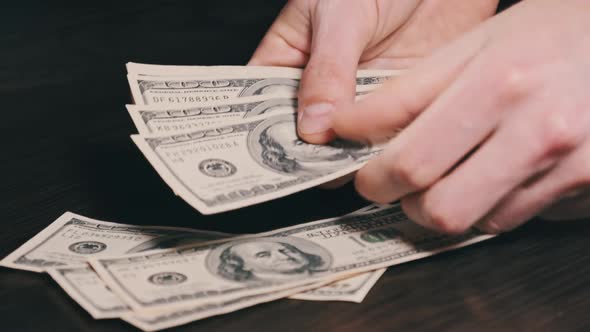 Counting Old Hundred Dollar Banknotes on a Black Wooden Table