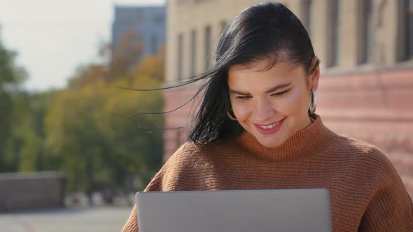 Closeup Young Happy Female Student Sitting Outdoors Looking at Laptop Screen Smiling Pleasant