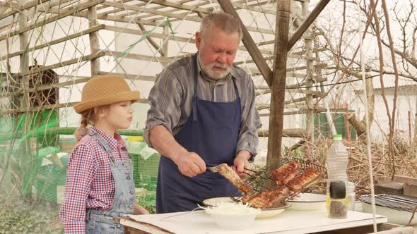 Grandfather and Granddaughter Remove Grilled Meat Kebab From the Grill Grate