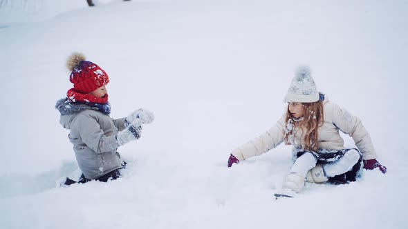 Beautiful children are standing out from white snow outdoors.