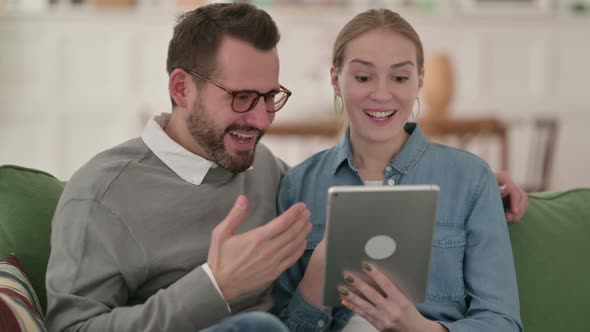 Couple Celebrating Success on Tablet at Home