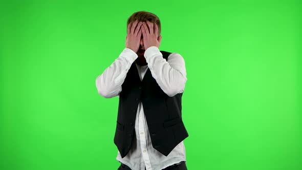 Man Carefully Examines Something Then Fearfully Covers His Face with His Hands. Green Screen