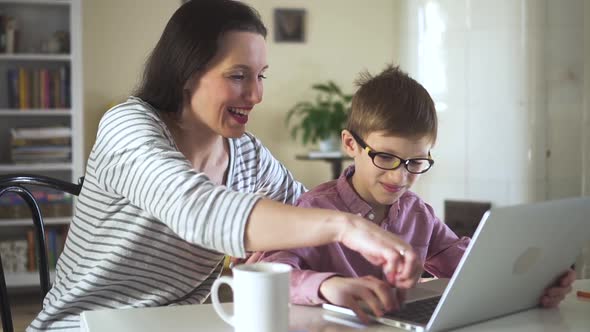 Modern Mother and Son Spending Time Together Sitting at Table with Laptop in Home Interior Spbd