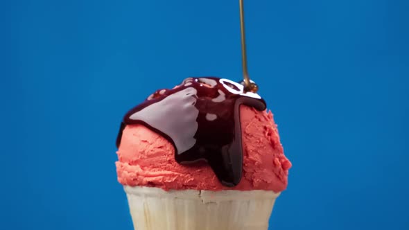 Rotating Strawberry Ice Cream in Cone with Caramel Sauce at Blue Background alt