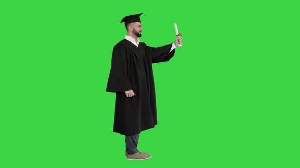 Happy Student Wearing the Graduation Robe and Holding His Certificate and Raising His Thumb Up on a