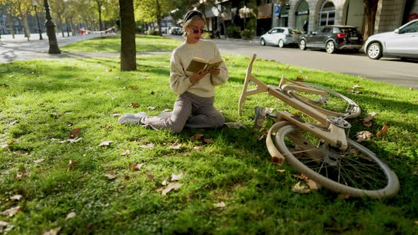 Woman Reading a Book in Park on the Lawn