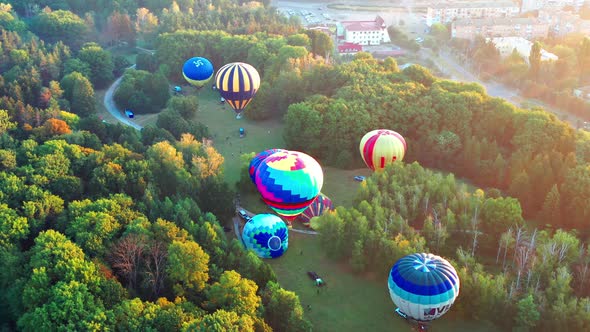 Beautiful sunbeams illuminate the balloons that fly over the park, green trees.