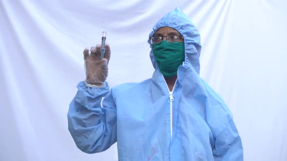 Doctor in PPE kit blue protective suit, surgical mask latex gloves. doctor holding syringe