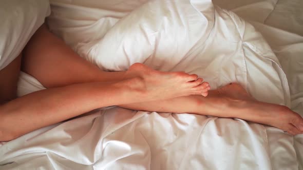 Beautiful Female Legs Gracefully Move in Bed in the Morning