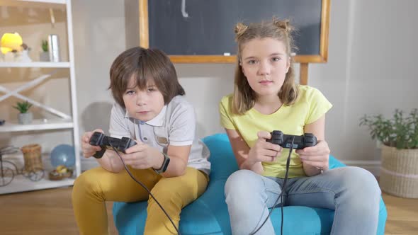 Happy Absorbed Caucasian Boy and Girl Using Game Consoles Playing Video Games