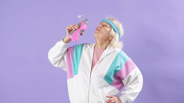 Senior Woman in Sportswear with a Bottle of Water Shows a Finger Up