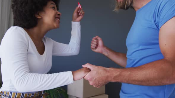 Happy mixed race couple holding house keys at new apartment house