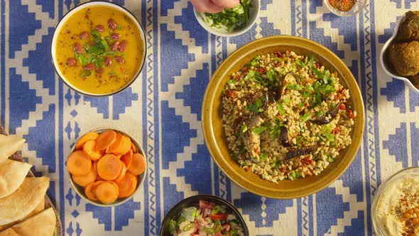 Adding Greenery in Bulgur with Eggplant Closeup Bean Soup Carrot Pita on Table