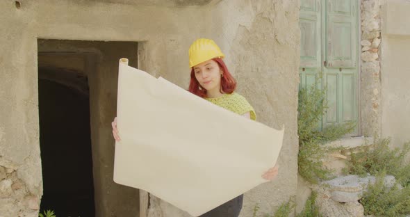 Young girl with helmet checks the project near a house in the city