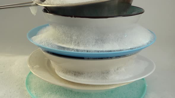 A stack of soapy dishes in foam.