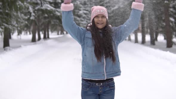 A Girl in a Good Mood Throws Snow Over Her Head and Whirls in the Winter Forest