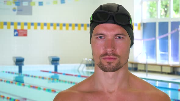 A Professional Swimmer Looks Seriously at the Camera at an Indoor Pool