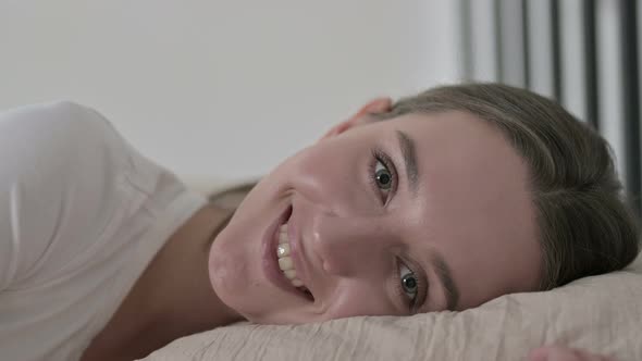 Cheerful Young Woman in Bed Smiling at Camera