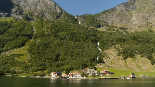 Small Town Under Huge Waterfall In The Fjords Of Norway