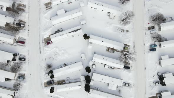 Top down aerial view over mobile home park after snow storm. Road recently plowed.