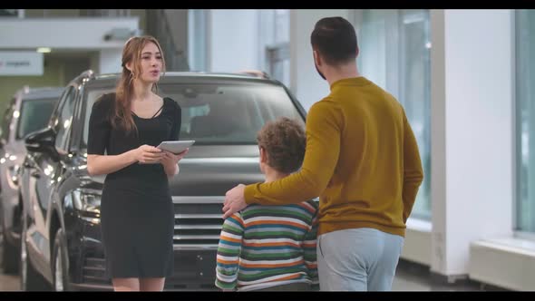Young Confident Caucasian Woman Explaining Car Specifications To Male Client