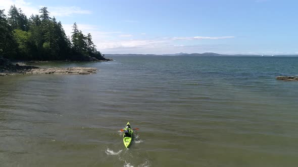 Rising Aerial Of Man Paddling Kayak Out To Sea Slow Motion alt