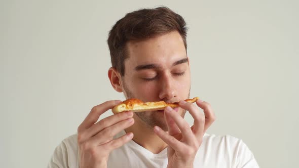 Closeup Face of Handsome Young Man Enjoying Sniffing Slice of Pizza and Eating on Delicious Food on