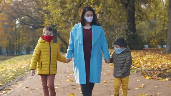 Mother and Two Little Children in Face Mask Walking in Autumn Park