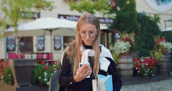 Female Student in Formal Clothes Holding Textbooks and Applying Her Mobile