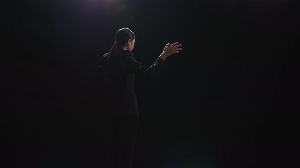 Back View Of Asian Speaker Woman Holding Her Hands Together While Speaking On Stage