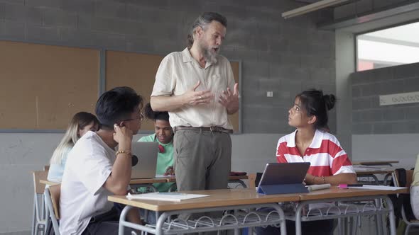 Professor Assisting Asian Students in Multi Ethnic Classroom