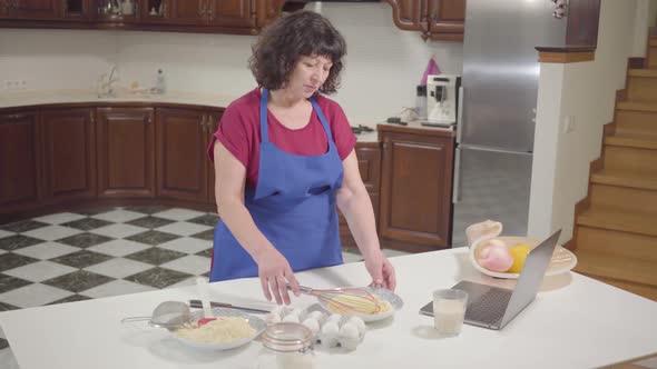 Brunette Caucasian Mature Woman Cooking at the Kitchen at Home