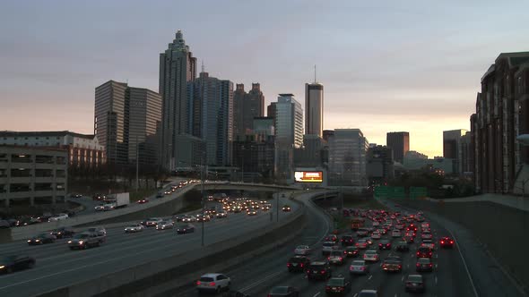 Static, wide shot of the Atlanta Skyline with traffic below in a darkening scene.