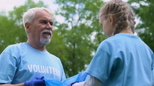 Little Girl Picking Litter in Park, Giving High-Five to Grandfather, Eco Project