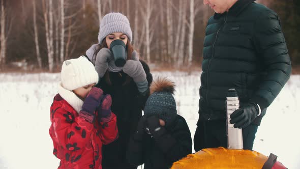 Family Drinking Hot Drinks From the Termos Near the Winter Forest