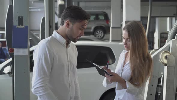 Handsome Male Manager Tells the Pretty Client How To Fill Out the Machine Repair Contract