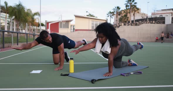 Curvy woman doing sport workout with her personal trainer outdoor