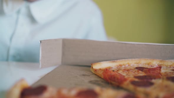 Schoolboy Eats Pizza with Sausage and Tomatoes at Table