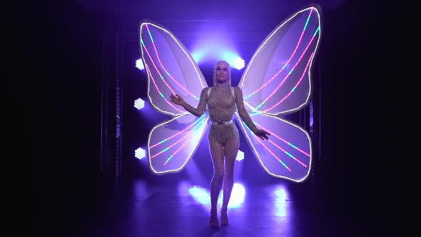 Slender Singer in a Tight-fitting Jumpsuit Strewn with Rhinestones, with Glowing Butterfly Wings